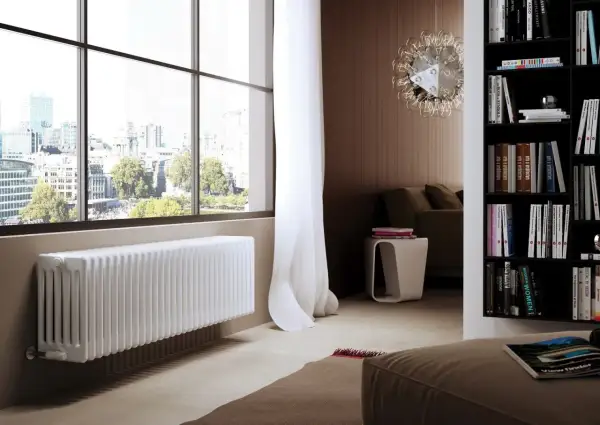 Un elegante termosifone bianco sotto una grande finestra con vista sulla città.