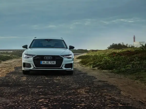 Audi A6 Avant blanche sur une route côtière. La plaque d'immatriculation "IN BE 719E" permet de connaître le modèle de voiture.