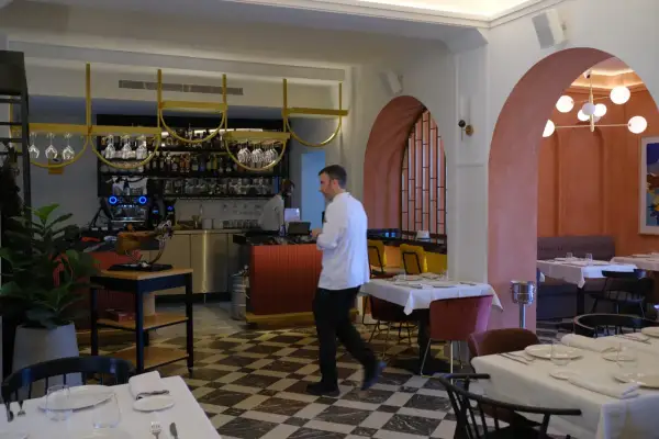 Interior de restaurantes arrabal Zaragoza. Mesas puestas, barra con botellas y un chef camina.