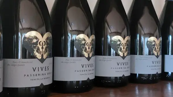 Bottiglie di Vives Passerina Brut, un vino fermo o frizzante, con etichetta a forma di cuore con teschio dorato.