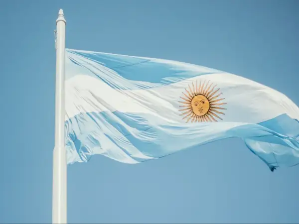 Flaga Argentyny powiewa na wietrze na tle błękitnego nieba.