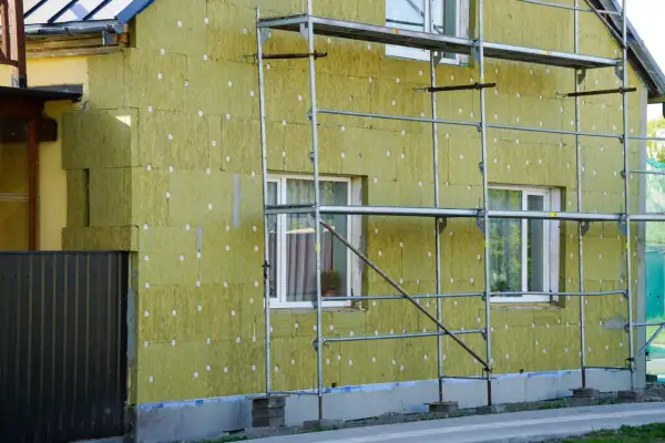 Dom w trakcie termomodernizacji, ocieplany wełną mineralną. Widać rusztowania i fragmenty starego muru pruskiego.