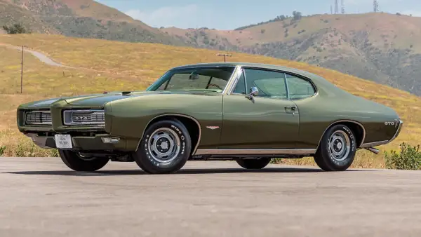 Zielony Pontiac GTO z 1969 roku na tle wzgórz. Klasyk amerykańskiej motoryzacji.