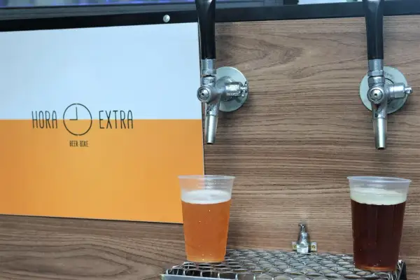 Dwa piwa w plastikowych kubkach pod kranikami. Jedno jasne, drugie ciemne. Logo "Hora Extra Beer Bike" z boku. Idealne na piwo bez chmielu.
