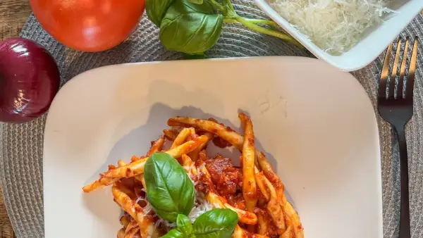 Makaron z sosem nduja, pomidorami, cebulą i bazylią. Pyszne danie, które wyjaśnia, nduja co to jest – pikantna, smarowna włoska kiełbasa.