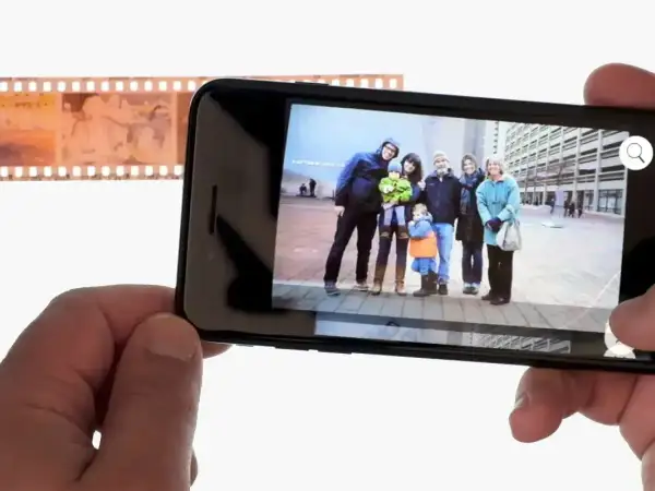 Telefon wyświetla zdjęcie rodziny, obok negatyw filmowy. Dowiedz się, jak odwrócić kolory zdjęcia na telefonie, by uzyskać ciekawy efekt.