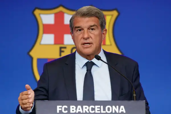 Prezydent FC Barcelona przemawia na tle herbu klubu, omawiając, ile Barcelona ma długu.