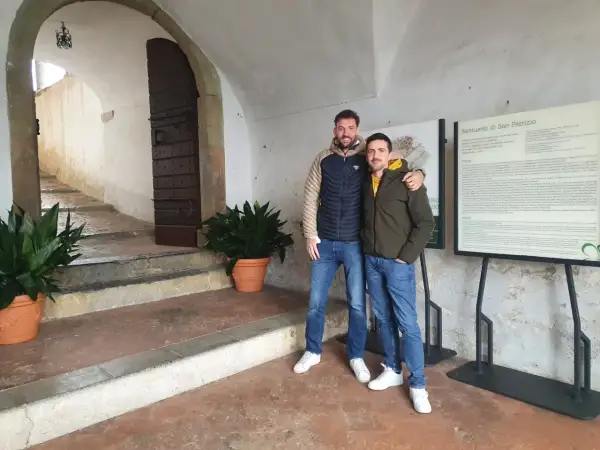 Due amici sorridono davanti al Santuario di San Patrizio, un luogo storico.