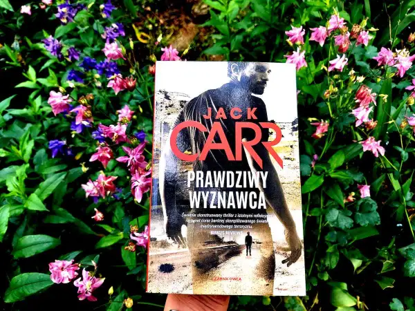 Prawdziwy Wyznawca" Jacka Carra, thriller w otoczeniu kwitnących kwiatów.