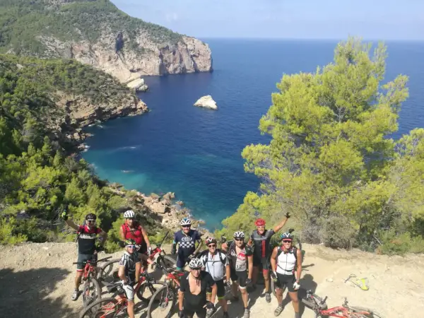 Grupo de ciclistas disfrutando de una ruta de ibiza en bicicleta con vistas espectaculares al mar Mediterráneo.