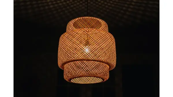 Pleciona, bambusowa lampa ruchoma rzuca na sufit cień przypominający siatkę.