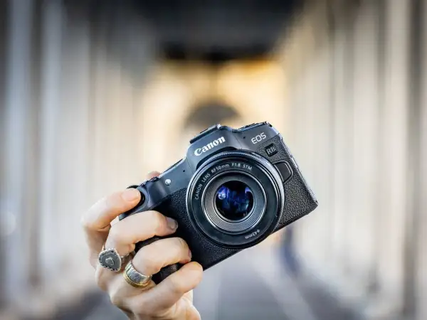 Mano che tiene una fotocamera Canon EOS R8 con obiettivo 50mm f/1.8 STM. Un modello compatto, ideale per chi cerca la qualità di un sensore canon apsc.