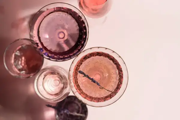 Różowe drinki w kieliszkach, jeden z gałązką lawendy. Idealny szłeps na letnie popołudnie.