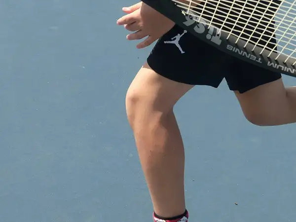 Tennisspelare med ont i ljumsken tips. En person i svarta shorts med Jumpman-logga på en blå tennisbana.