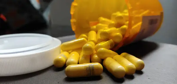 Gula kapslar, en del av en burk, ligger utspridda. En kapsel visar texten "gabapentin 300 mg", en medicin som kan hjälpa mot ångest.