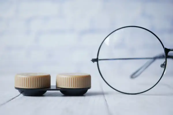 Dwa pojemniki na soczewki i okulary. Promień krzywizny soczewki okularów jest widoczny.