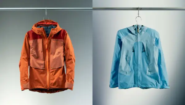 Deux vestes, une orange et une bleue, suspendues. La veste orange est mouillée, montrant l'efficacité du Gore-Tex.