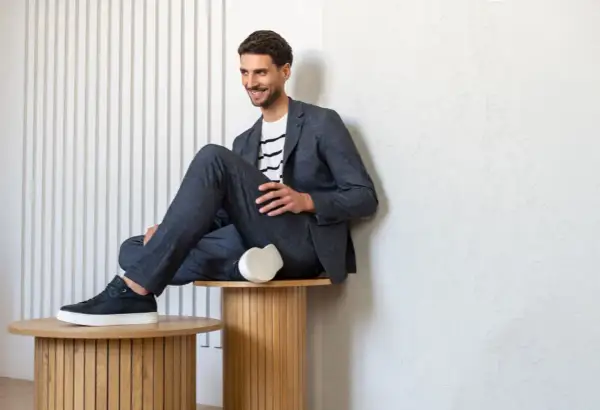 Uśmiechnięty mężczyzna w granatowym garniturze i pasiastym T-shircie, prezentujący styl smart casual.