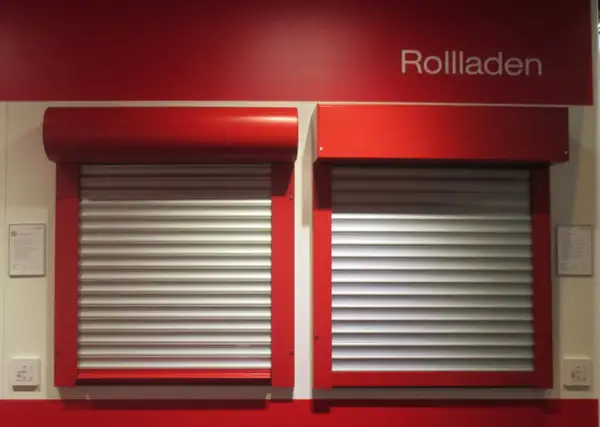 Dwie czerwone rolety zewnętrzne z aluminiowymi lamelami, prezentujące rozwiązania do ocieplenia domu.