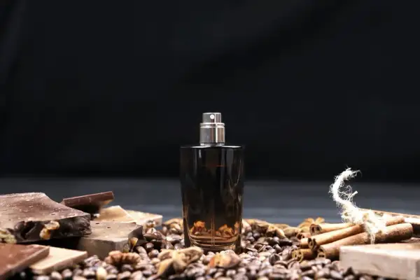 Męskie perfumy arabskie w ciemnej butelce, otoczone czekoladą, kawą i cynamonem.