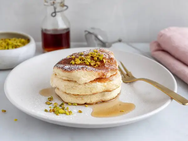 Fluffiga japanska pannkakor toppade med pistagenötter och pudersocker, serverade med sirap.