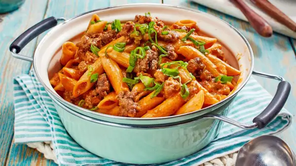 Herzhaftes One Pot Pasta mit Hackfleisch und einer cremigen Tomatensoße, garniert mit Frühlingszwiebeln.