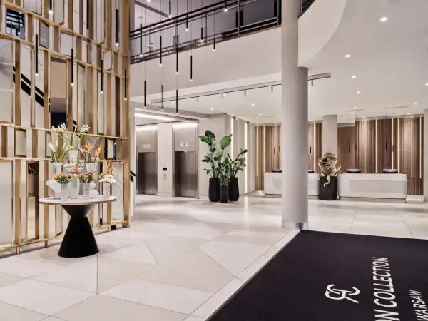 Eleganckie lobby hotelu Radisson Collection Hotel Warsaw z nowoczesnymi windami, recepcją i dekoracjami roślinnymi.