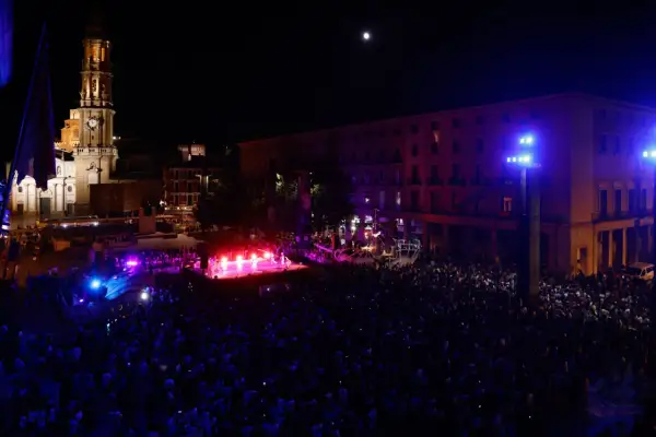 Multitud celebra la **noche blanca Zaragoza** ante un escenario iluminado y la Basílica del Pilar.