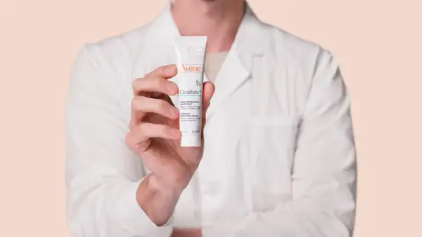Mano sosteniendo un tubo de crema Avène Cicalfate+, ideal para piel irritada.