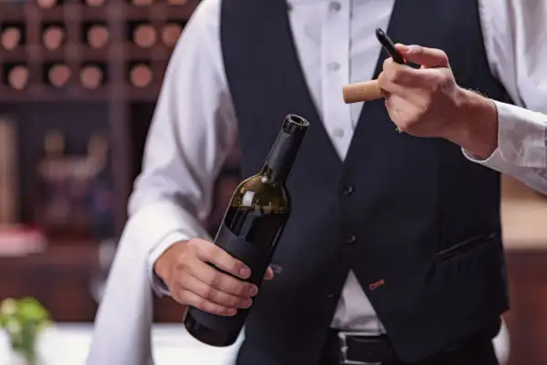 Un sommelier mostra come usare cavatappi per aprire una bottiglia di vino.