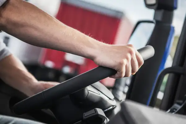 Main d'un conducteur sur le volant d'un camion. La question "carte fimo c'est quoi" pourrait être posée par quelqu'un qui apprend ce métier.