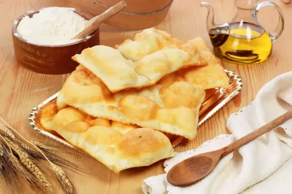 Piatto di gnocco fritto di Ferrara, dorato e soffice, con farina, olio e spighe di grano.