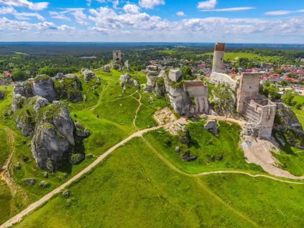 Malowniczy krajobrazowy park orlich gniazd z ruinami zamków na wapiennych skałach, zielone wzgórza i błękitne niebo.