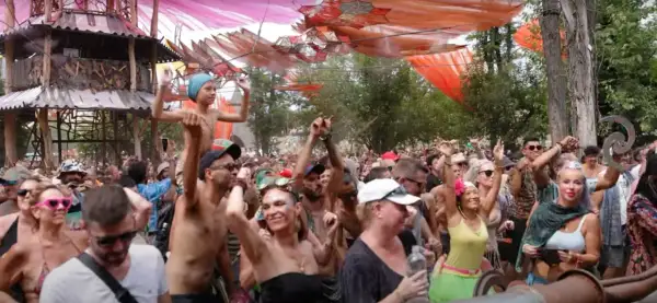 Multitud bailando en un festival psytrance España, con decoraciones coloridas y una estructura de madera.