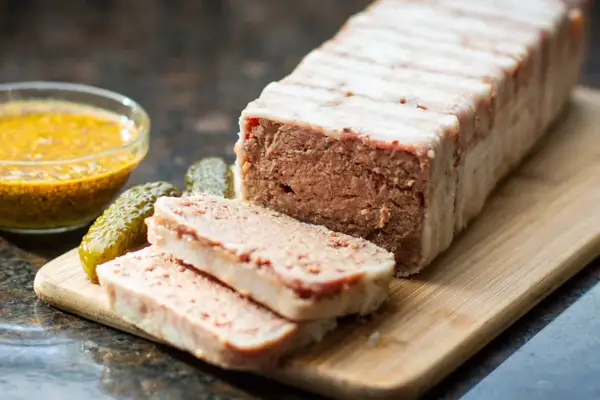Pyszny pasztet zawinięty w boczek, pokrojony na plastry, z ogórkami i musztardą. Idealny na kanapki, zastanawiasz się, ile pieczemy pasztet?