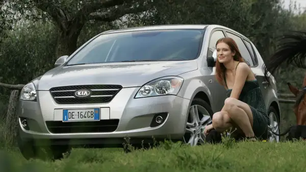 Srebrny Kia Ceed kombi 2009 na tle natury, z kobietą i końmi.
