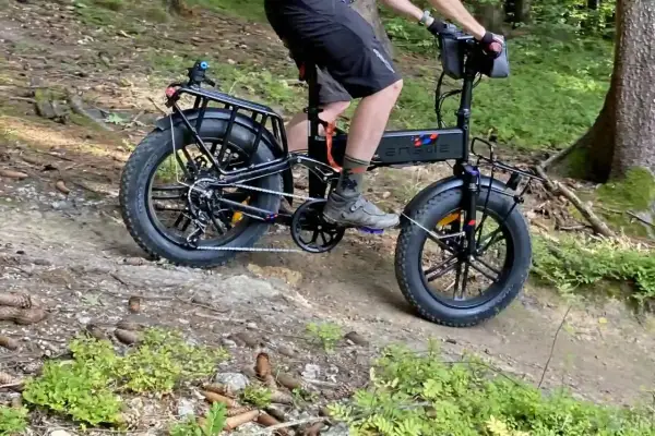 Rowerzysta na rowerze elektrycznym z grubymi oponami pokonuje leśną trasę rowerową.