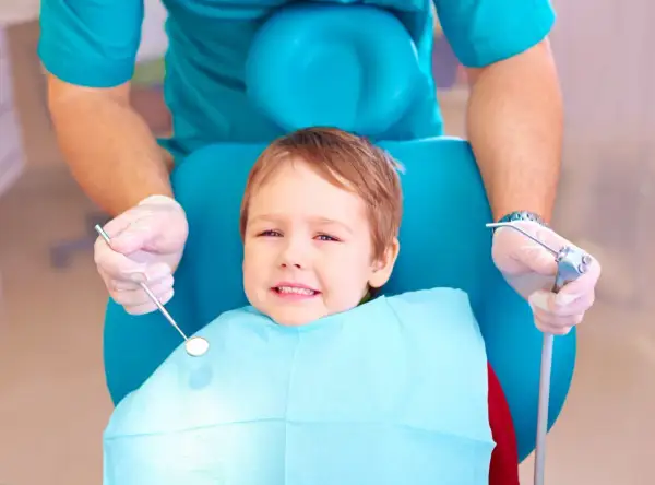 Mały pacjent u dentysty, który bada ząbki. Warto wiedzieć, co na ból zęba u dziecka, by szybko ulżyć maluchowi.