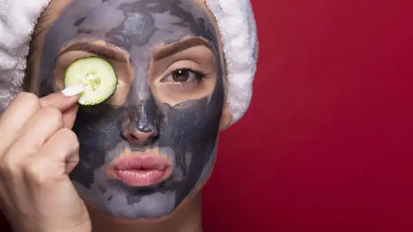 Donna con maschera viso all'argilla e fetta di cetriolo sull'occhio. La maschera viso a cosa serve? A purificare e rinfrescare la pelle.