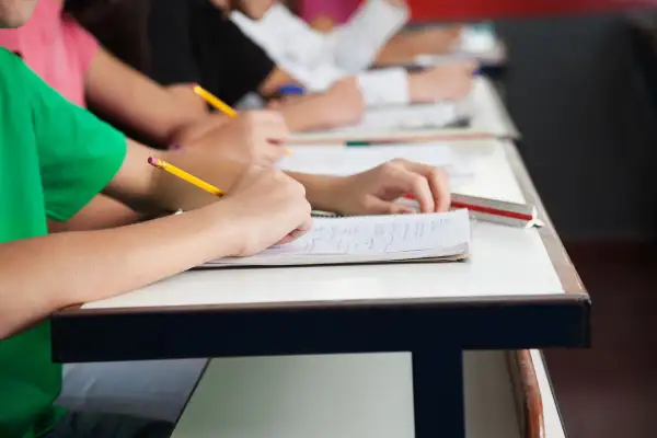 Schüler schreiben in ihren Heften. Ein Bleistift liegt bereit, um die Fortschritte im formative assessment festzuhalten.