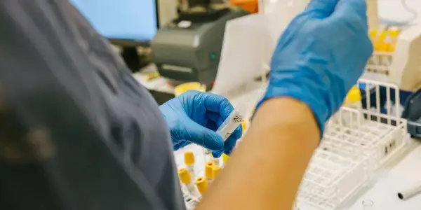 Laborant hanterar provrör i laboratoriemiljö, en del av forskningen kring anhedoni behandling.