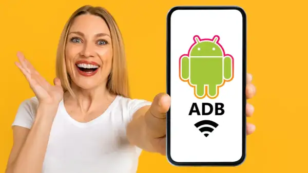 Mujer sorprendida muestra un teléfono con el logo de Android y "ADB" escrito, indicando control remoto.
