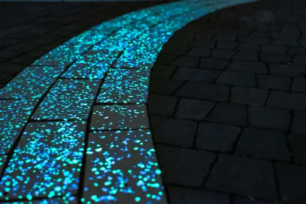 Ścieżka z luminescencyjnej kostki wokół pomnika, nocą mieniąca się błękitno-zielonym blaskiem.