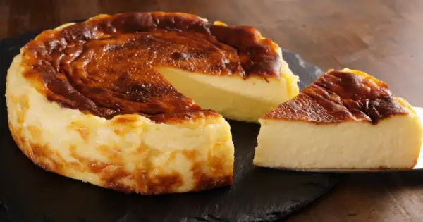 Pyszny, lekko przypieczony sernik na czarnej desce. Nawet jeśli sernik kcal kusi, warto spróbować!