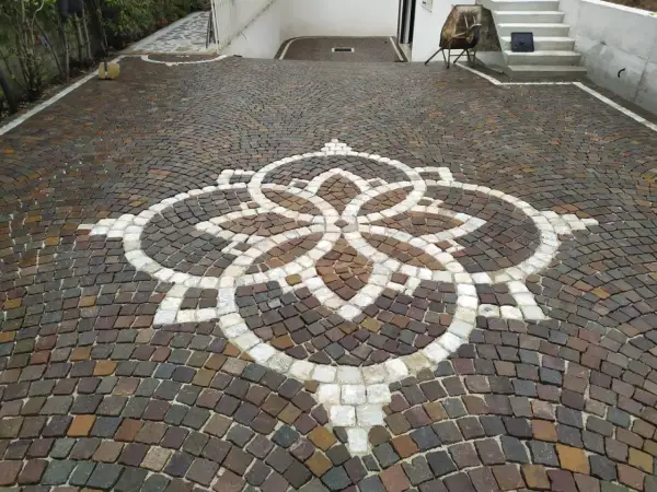 Vicolo carrabile in porfido con un elegante motivo floreale centrale.