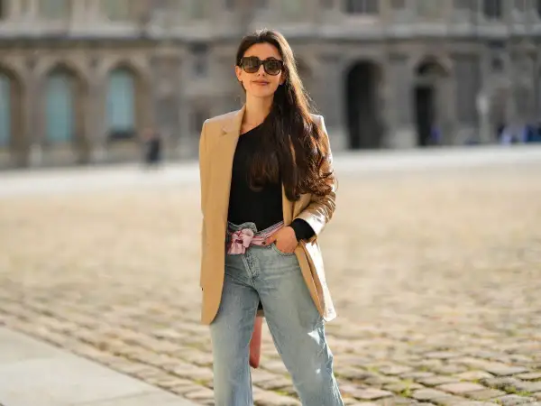 Stylowa kobieta w beżowej marynarce i jeansach mom fit. Jej stylizacje to kwintesencja miejskiego szyku.