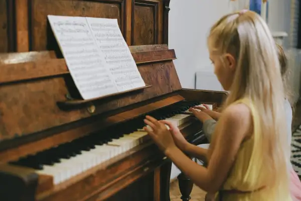 Dzieci grają na keyboardzie, patrząc na nuty literowe.