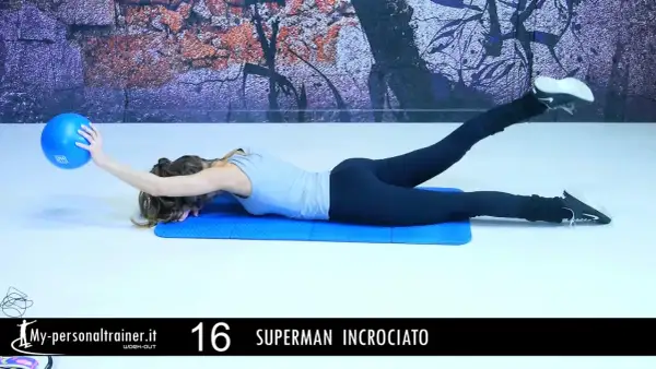 Donna esegue esercizio "Superman incrociato" per rafforzare i lombari muscoli, sollevando una gamba e un braccio con una palla blu.