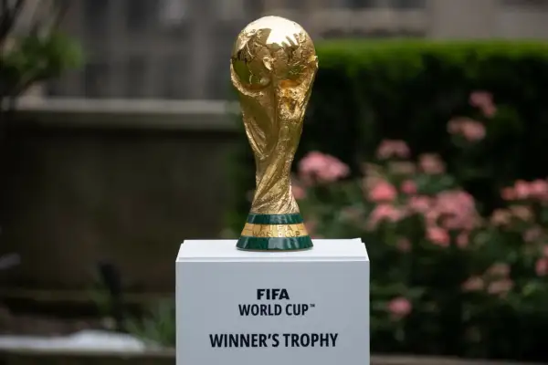 Złoty Puchar Świata FIFA, marzenie każdego z gospodarzy mistrzostw świata w piłce nożnej, lśni na tle zieleni i różowych kwiatów.