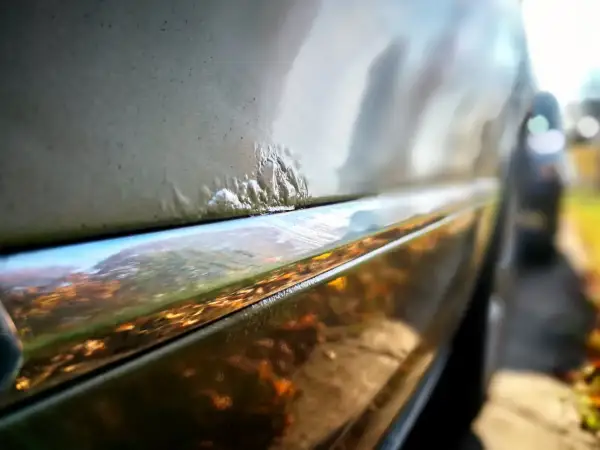 Nahaufnahme von Rostblasen am Auto, die eine Rostbehandlung am Auto erfordern.